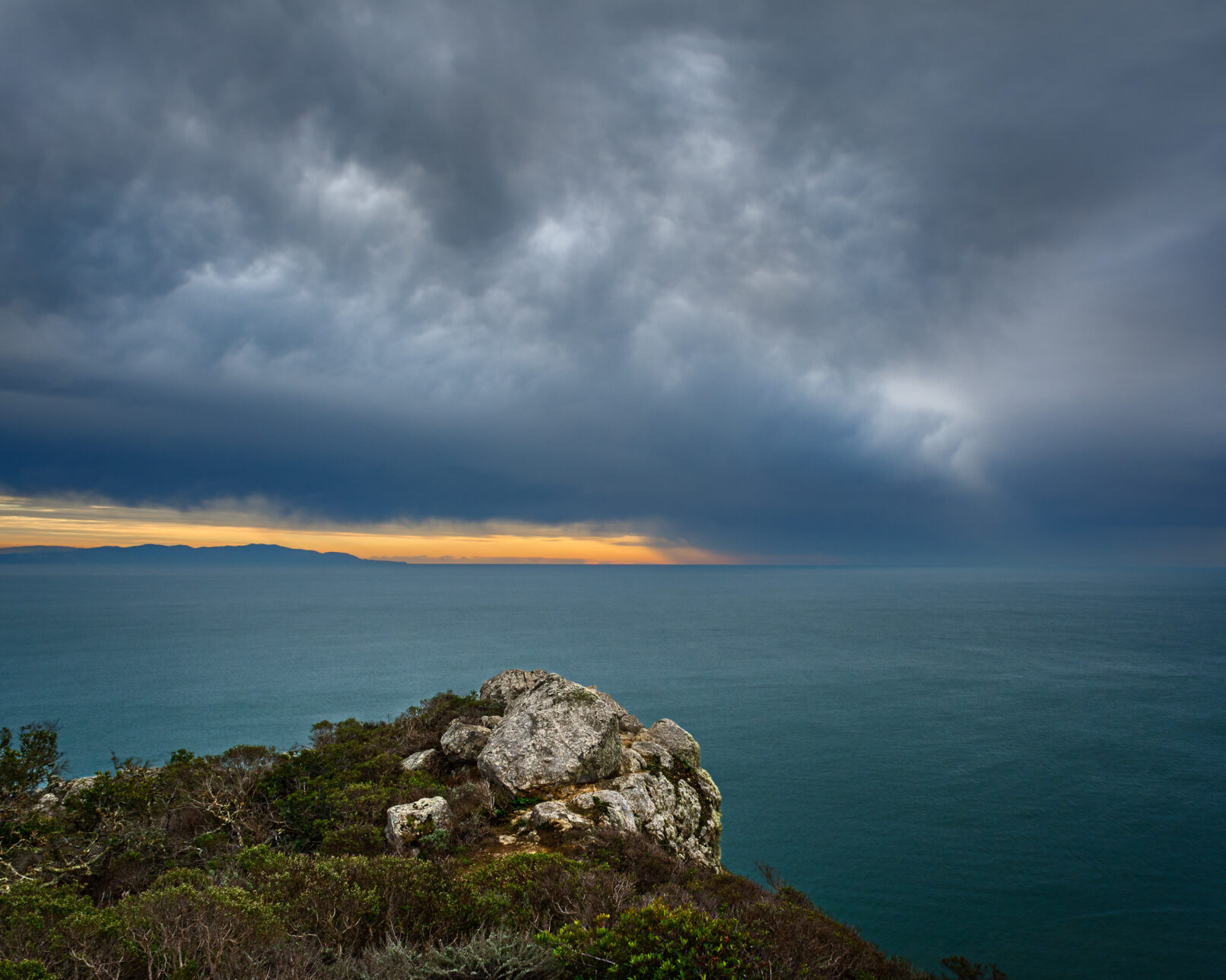 California coast cliff rock and ocean with storm in distance